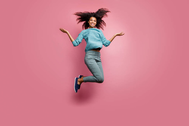 Turned full length body size photo of cheerful toothy beaming cute nice pretty woman in grey pants throwing her hair up jumping blue jumper isolated pastel color background - Fotó, kép