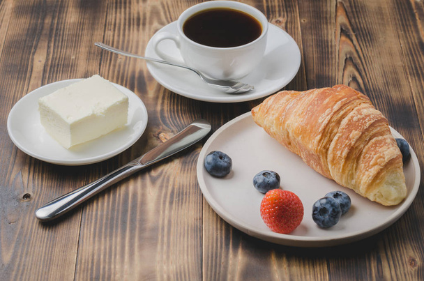 Coffee cup, croissant with berries in white bowl and butter on w - Foto, Bild