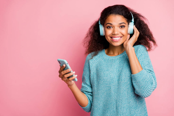 Photo of curly wavy cheerful nice woman wearing headphones modern technology standing near empty space with telephone isolated pastel color background - Φωτογραφία, εικόνα