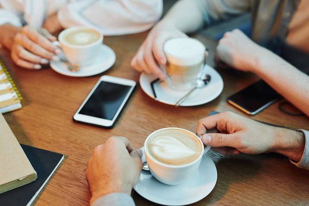 Mains d'amis réunis par table en bois dans un café et ayant cappuccino tout en passant du temps ensemble
 - Photo, image