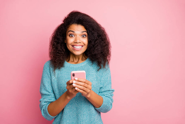 Photo of curly wavy cheerful excited ecstatic woman browsing through telephone receiving notifications with positive feedback isolated pastel color background - Фото, зображення