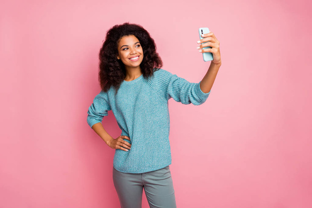 Photo of curly wavy cheerful nice pretty woman standing confidently with hands on waist holding telephone taking selfie to send isolated in grey pants pastel color background - Fotó, kép