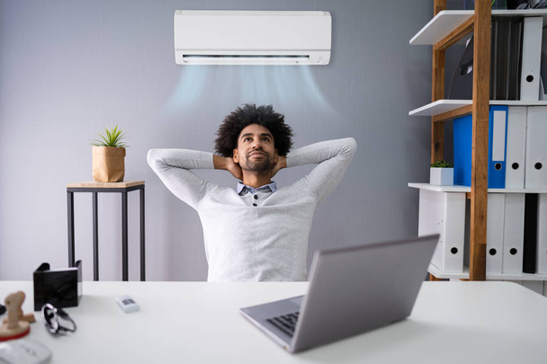 Happy Young Businessman Working In Office With Air Conditioning - Photo, image
