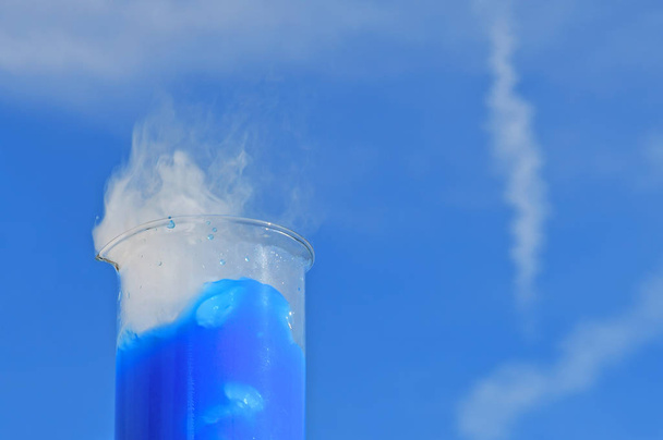 La fumée blanche provient d'un bécher avec une solution bleue de fluorescéine après addition de glace sèche. Expérience de démonstration chimiste
. - Photo, image