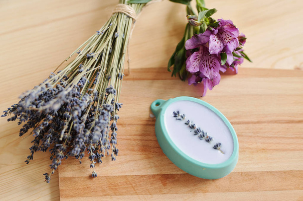 Übersicht über Bündel von frischem Lavendel und lila Amaryllis und Silikonform gefüllt mit flüssiger Seifenmasse auf Holzgrund - Foto, Bild
