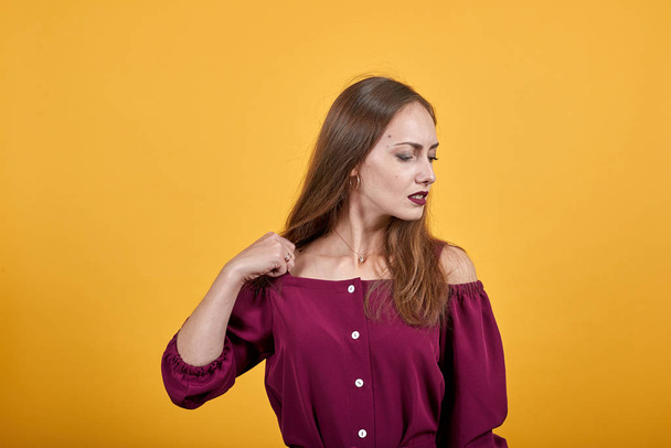 Ginger girl in burgundy bluse with bow over isolated orange background - Fotó, kép