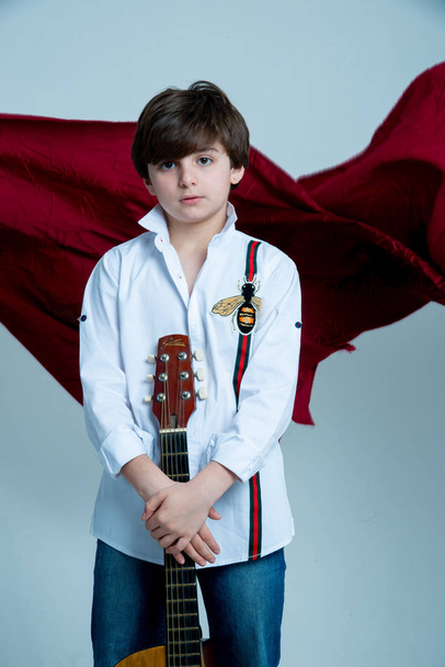 boy posing with acoustic guitar on photo studio on gray background - Foto, afbeelding