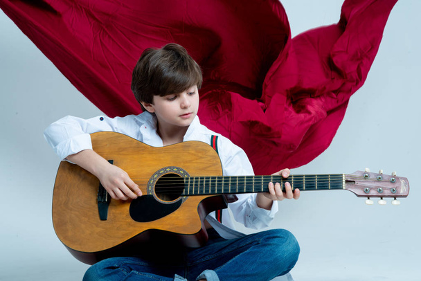 boy kid playing on acoustic guitar on photo studio - 写真・画像