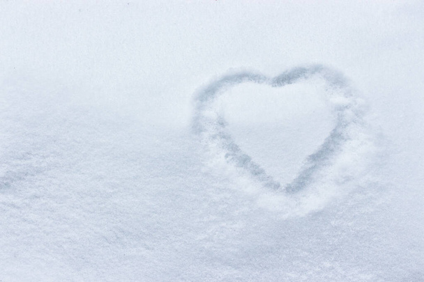Heart in the snow, hands drawing on a clean empty snow surface, winter cold. Concept of love, love message winter outdoors - Foto, Imagem