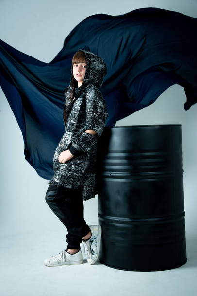 boy in black zip hoodie standing with black barrel on photo studio - Photo, image