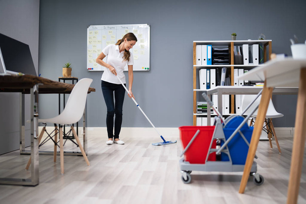 Full Length Of Female Janitor Mopping Floor In Office - Foto, Imagem