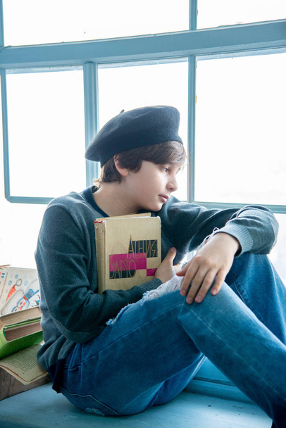 boy kid portrait with book siting on windowsill  - Фото, изображение