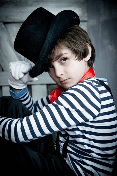 cute boy in mime costume sitting on wooden sofa in photo studio - Foto, Imagem