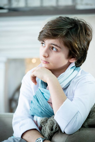 cute boy portrait in stylish scarf sitting on armchair on winter background  - Photo, image