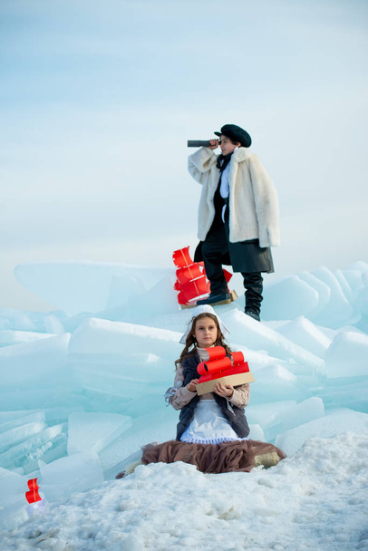 girl and boy looking in telescope and standing on ice on winter background - Zdjęcie, obraz