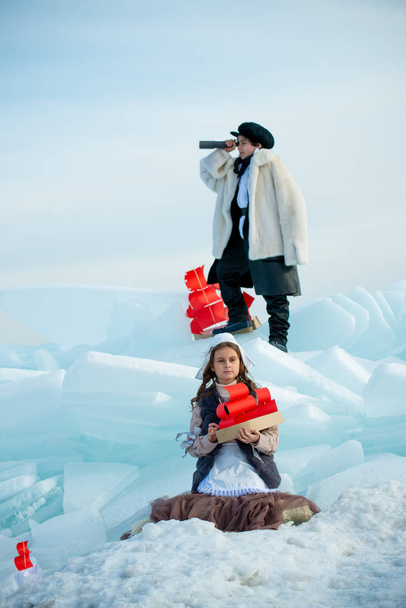 girl and boy looking in telescope and standing on ice on winter background - Zdjęcie, obraz