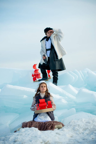 children playing on iceberg with wooden ship toys on winter background - Фото, изображение