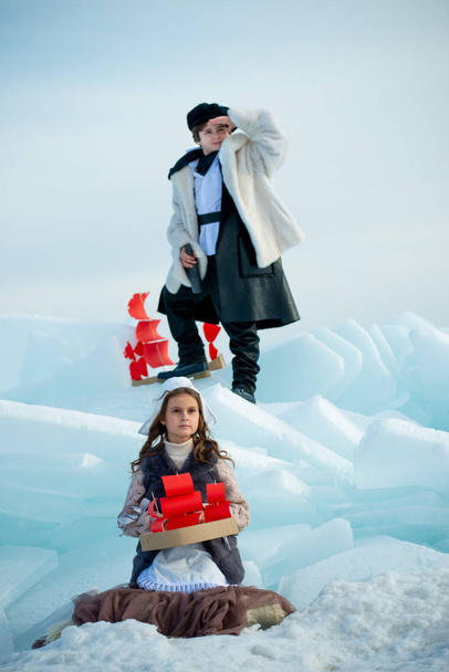 children standing on iceberg with wooden ship toys on winter background - Photo, Image