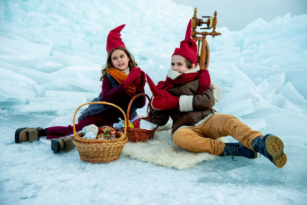 children in red gnome caps on winter picnic on snow  background  - Foto, Imagem
