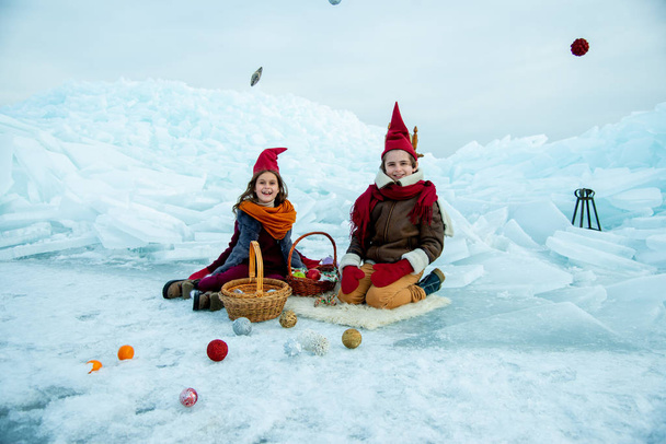 children in red gnome caps on winter picnic on snow  background  - Fotografie, Obrázek