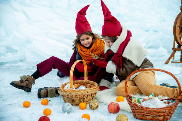 children in red gnome caps on winter picnic on snow  background  - Foto, imagen