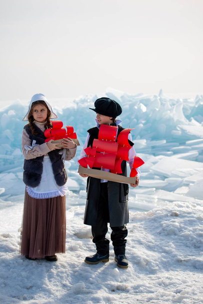children standing on iceberg with wooden ship toys on winter background - Zdjęcie, obraz