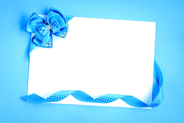 Порожня паперова нота з синіми стрічками в точках полоки і носом на синьому фоні
. - Фото, зображення
