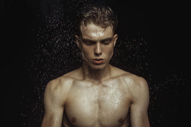 Handsome wet sport sexy stripped guy portrait with waterdrops and smoke on isolated black background - 写真・画像
