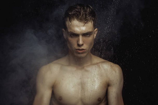 Handsome wet sport sexy stripped guy portrait with waterdrops and smoke on isolated black background - Foto, Imagem