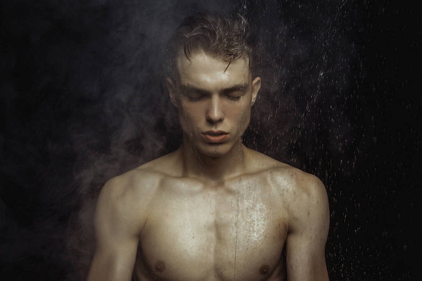 Handsome wet sport sexy stripped guy portrait with waterdrops and smoke on isolated black background - Foto, afbeelding
