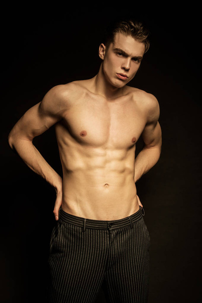 Muscle strong beautiful stripped male model in black jeans on black isolated font background - 写真・画像