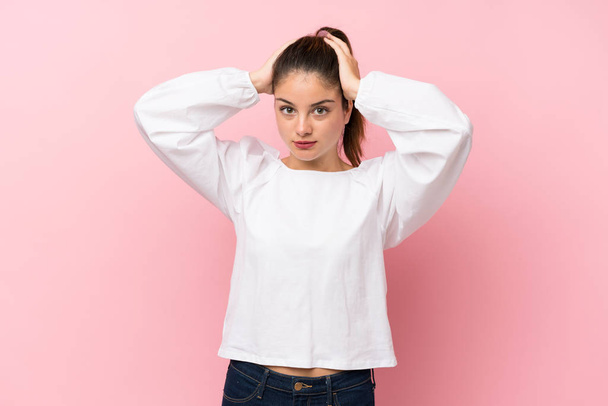 Young brunette girl over isolated pink background frustrated and takes hands on head - Photo, Image