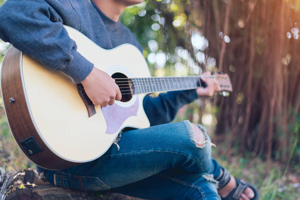 Homem tocando uma guitarra acústica no parque, Close-up
 - Foto, Imagem