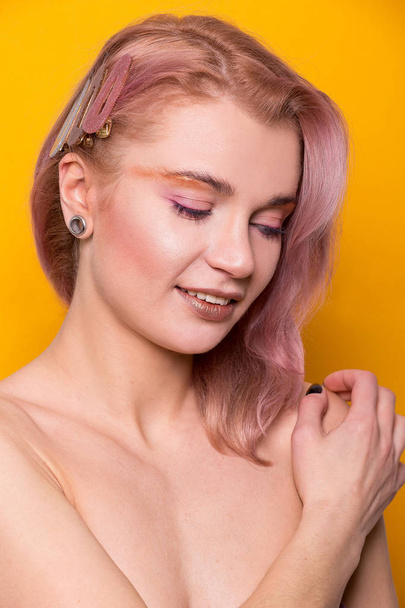 Shiny golden make-up on a beautiful young European model girl isolated on an orange background in the photo studio - Valokuva, kuva