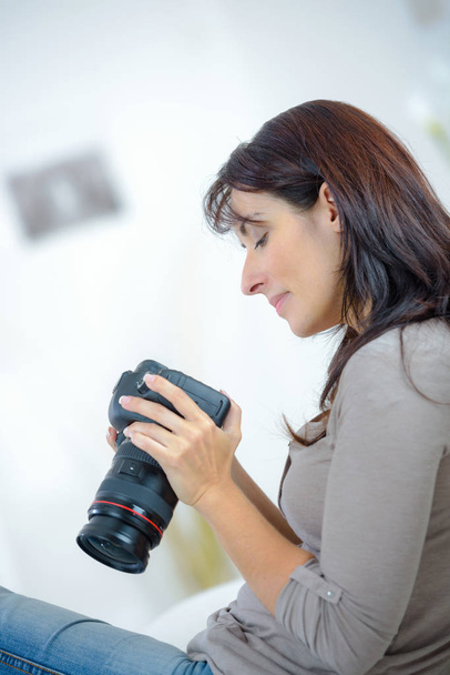 female photographer sitting at home checking camera - Foto, imagen