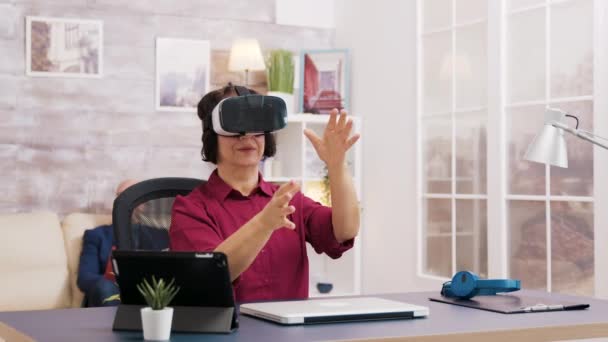 Elderly age woman using virtual reality goggles in living room - Filmmaterial, Video
