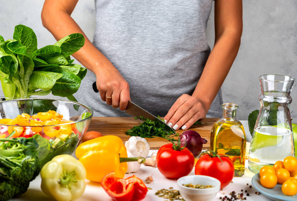 Kadın mutfakta sebze keser ve salata pişirir. Sağlıklı diyet kavramı. - Fotoğraf, Görsel