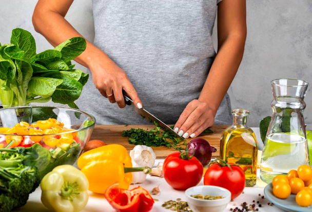 La mujer corta verduras y cocina ensalada en la cocina. Concepto de dieta saludable
. - Foto, imagen