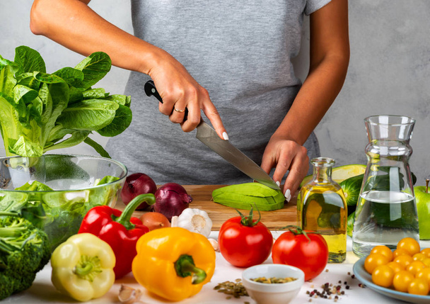 Kadın avokado keser ve mutfakta salata pişirir. Sağlıklı diyet kavramı. - Fotoğraf, Görsel