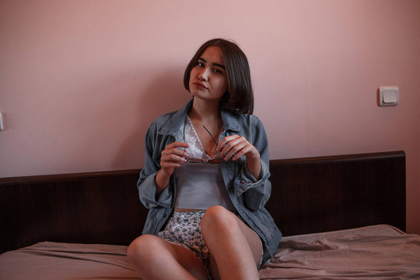 a young girl with short hair in a denim jacket and shorts sits a - Fotó, kép