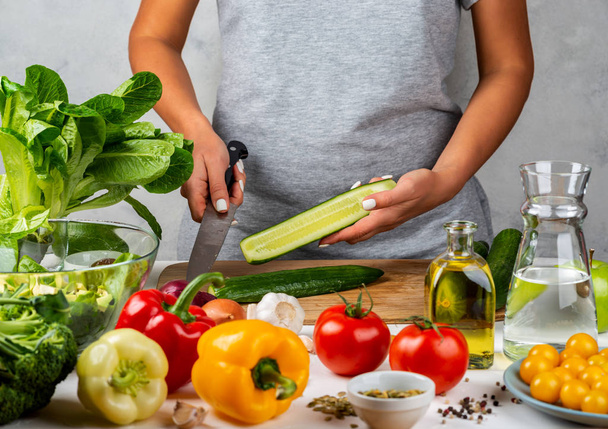 Женщина режет огурец, готовит салат на кухне. Концепция здорового питания
. - Фото, изображение
