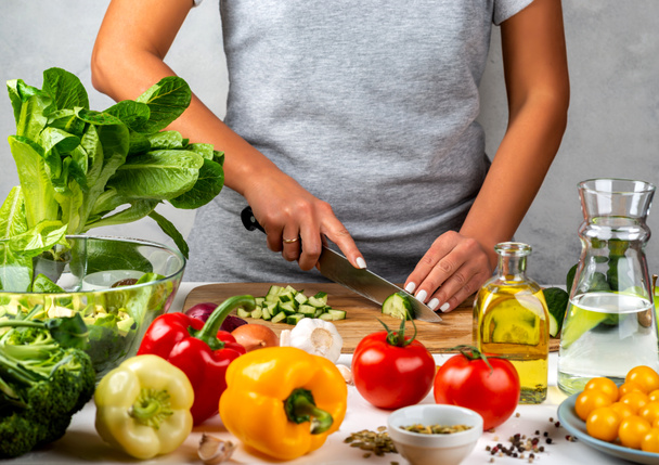 Kadın salatalık keser, mutfakta salata pişirir. Sağlıklı diyet kavramı. - Fotoğraf, Görsel