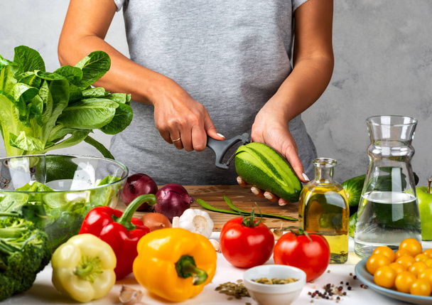 Woman is peeling avokado, cooking salad in the kitchen. Healthy diet concept. - Fotó, kép
