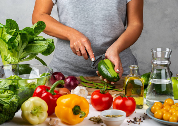 Kadın avokado soyuyor, mutfakta salata pişiriyor. Sağlıklı diyet kavramı. - Fotoğraf, Görsel