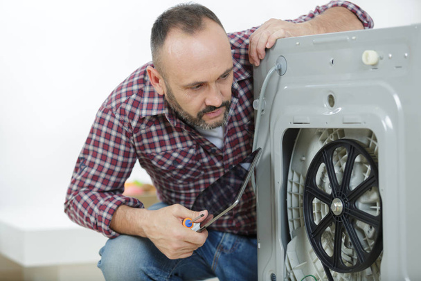 professional worker estimating cost for broken washing machine - Foto, Imagen