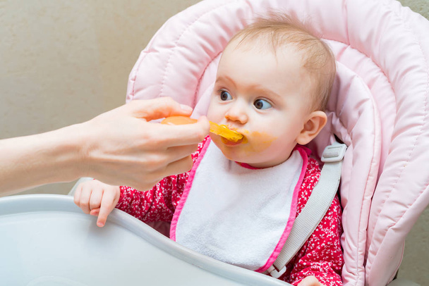 Feeding cute baby girl in pram with spoon - Photo, Image
