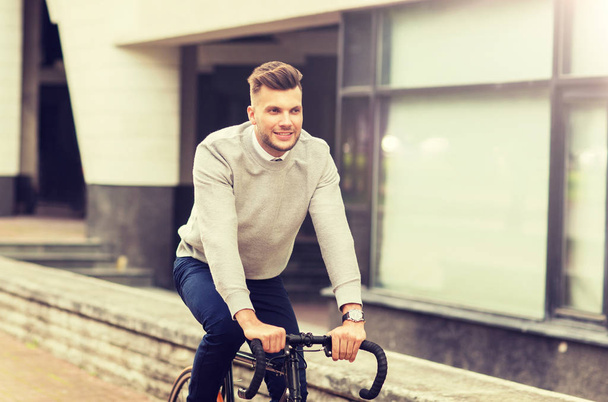young man riding bicycle on city street - Zdjęcie, obraz