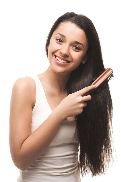 Beautiful young girl combing her hair - Фото, изображение