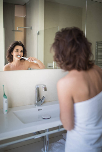 Pretty, middle aged woman brushing her teeth - Zdjęcie, obraz