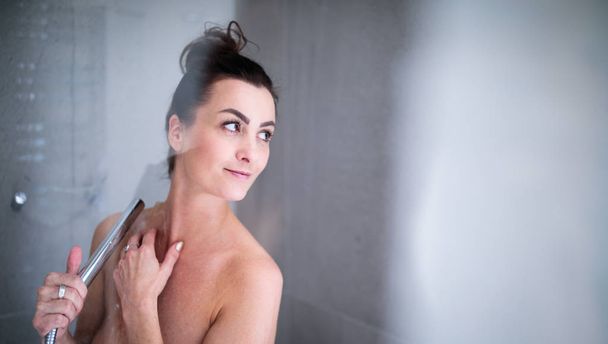 Pretty, young woman taking a long hot shower washing her hair  - Foto, afbeelding
